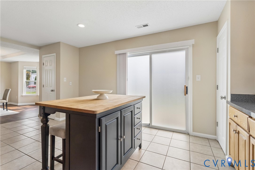 Kitchen featuring a central island with a wood countertop, painted cabinetry, and integrated seating