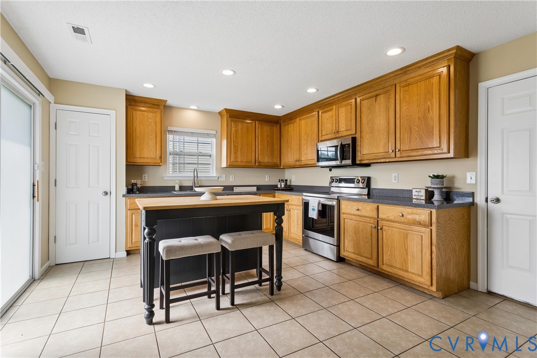 Kitchen featuring oak cabinetry with crown molding, dark countertops, and stainless steel appliances