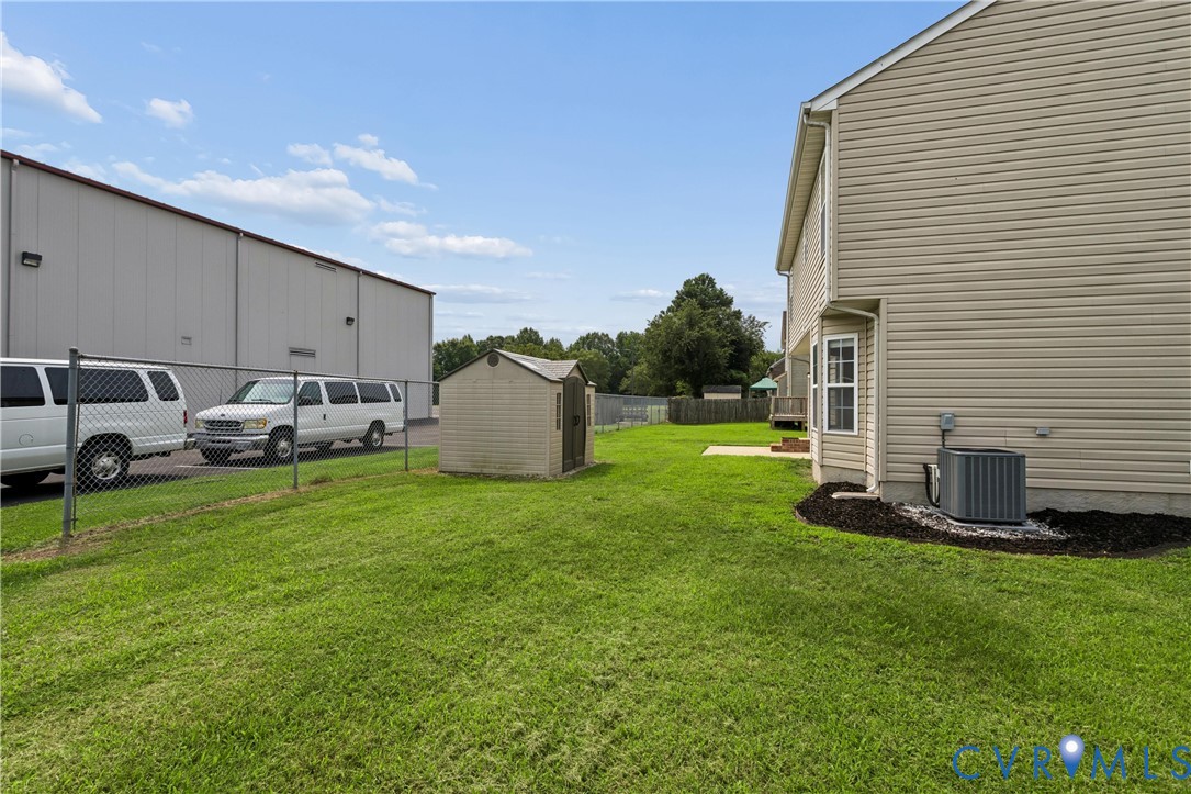 Grassy side yard featuring a functional storage shed and chain-link fencing