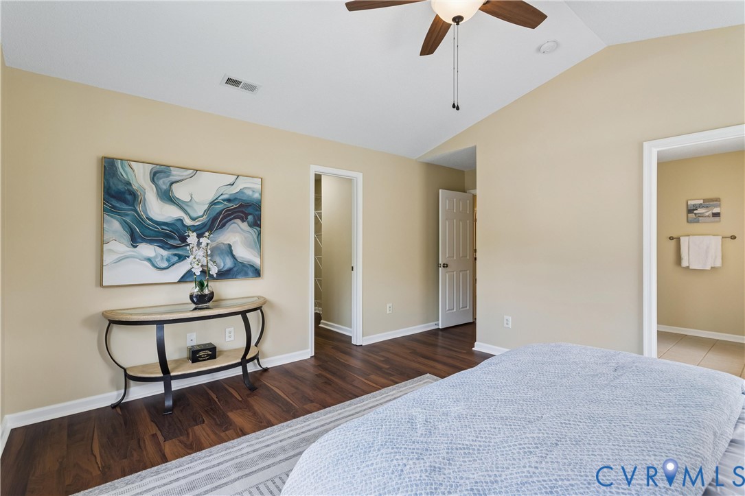 Room featuring wood-finish flooring, vaulted ceiling, and a ceiling fan with integrated lighting