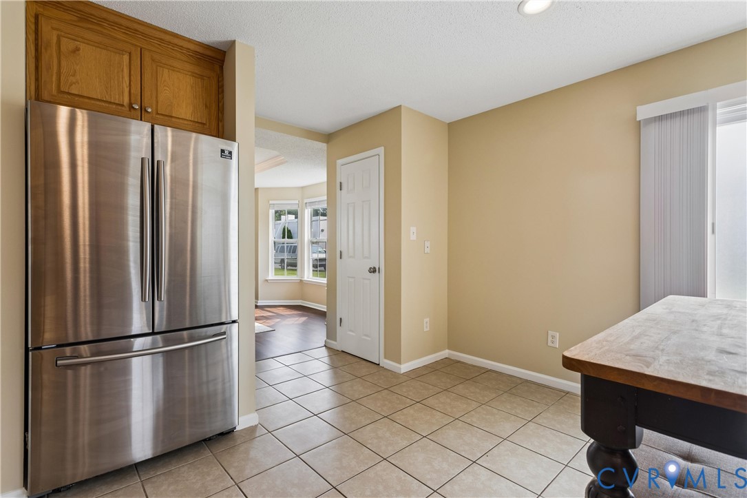 Kitchen area featuring tile flooring, stainless steel refrigerator, and recessed lighting