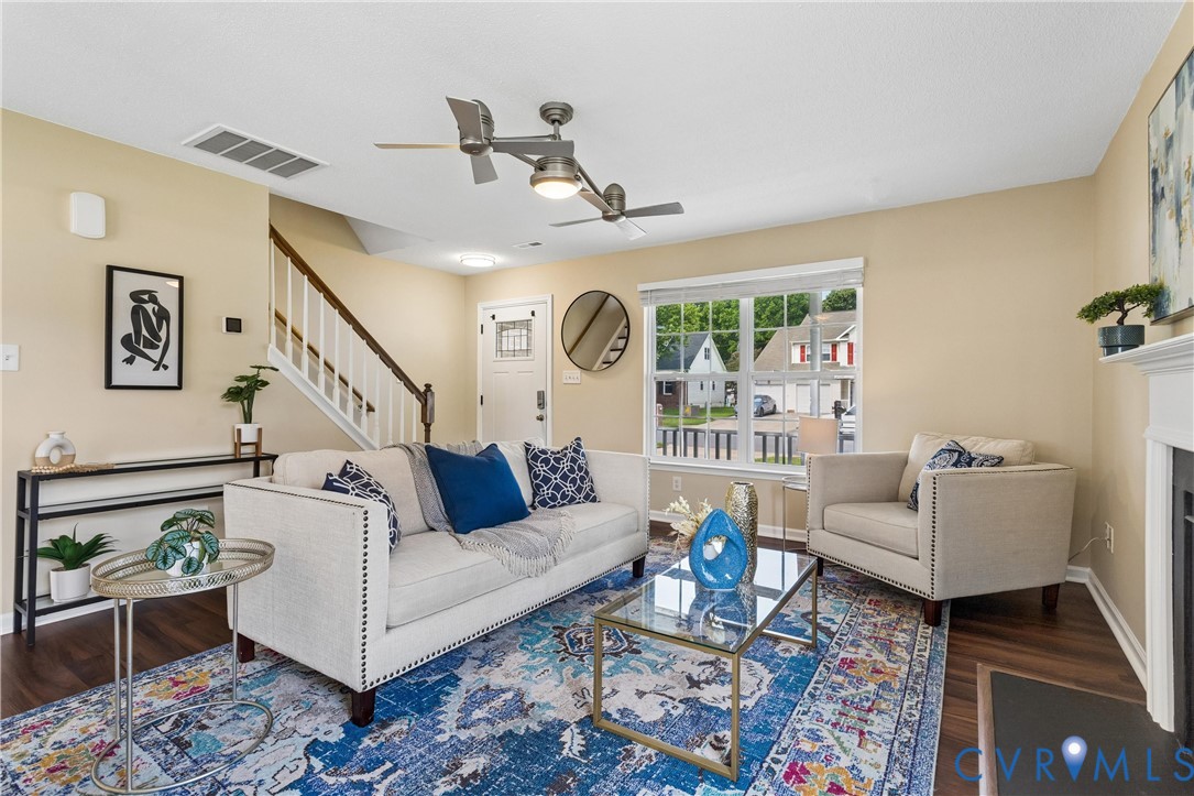 Living area featuring wood-finish flooring, a white trim window, and dual ceiling fans Living area featuring wood-finish flooring, a white trim window, and dual ceiling fans