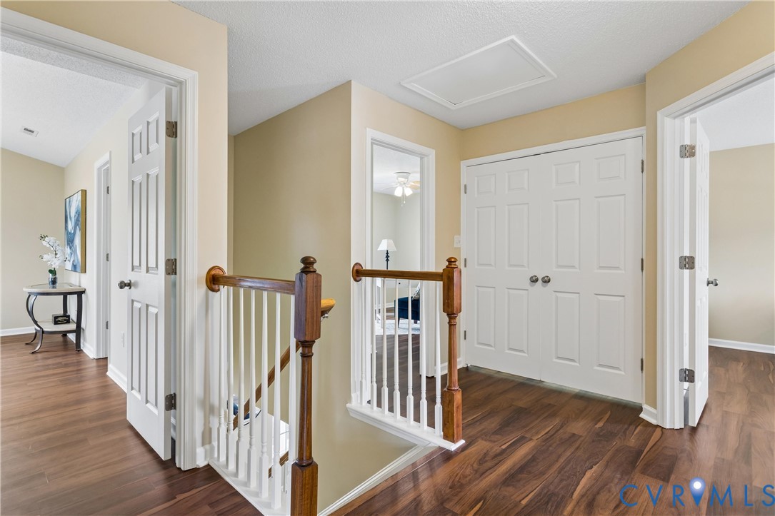 Upper-level hallway featuring wood-finish flooring, light tan wall color, white trim, and white paneled doors