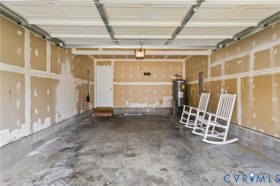 Two-car garage featuring a concrete floor, exposed drywall, and a white overhead door