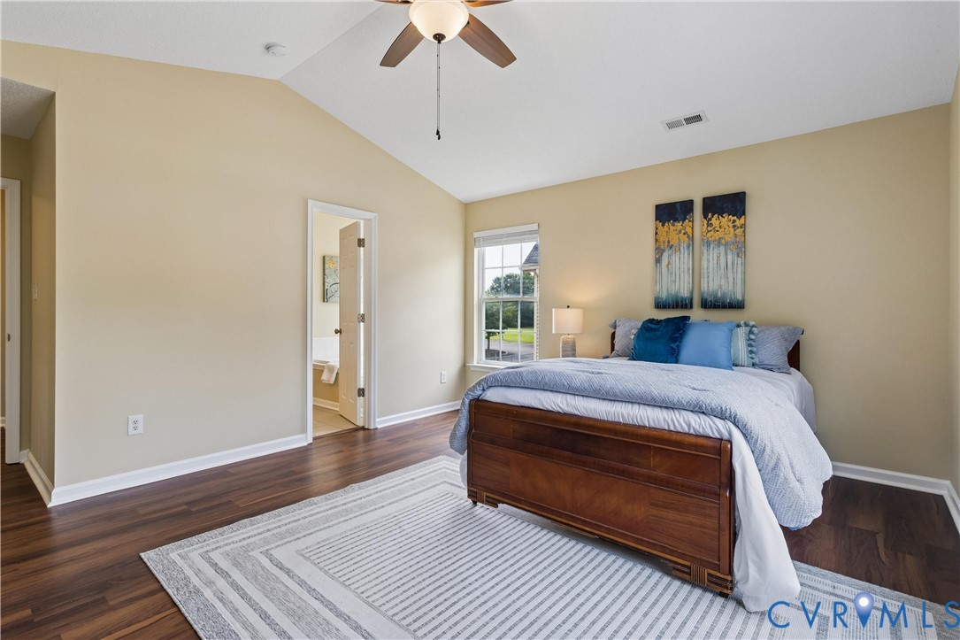Vaulted ceiling bedroom featuring wood-finish flooring and a ceiling fan