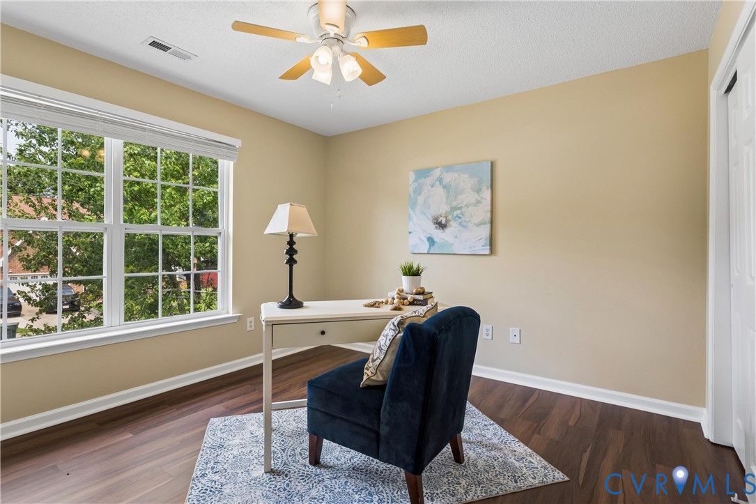 Room featuring wood-finish flooring, a multi-pane window with blinds, and a ceiling fan with light fixture
