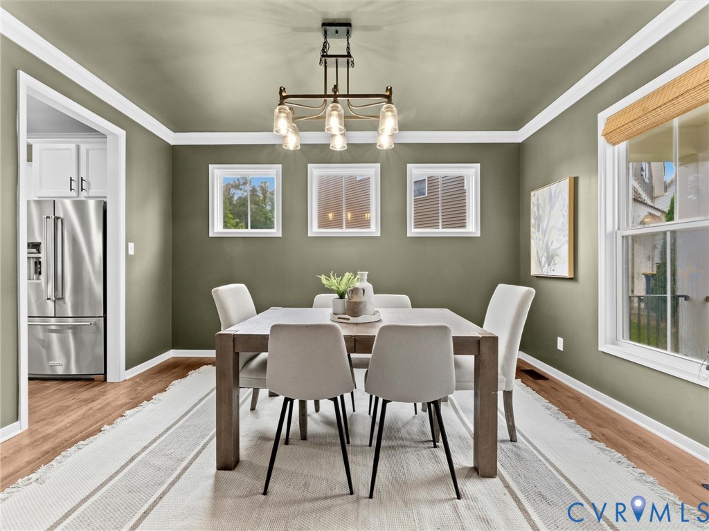 Dining area featuring wood-finish flooring, crown molding, and a contemporary chandelier Dining area featuring wood-finish flooring, crown molding, and a contemporary chandelier