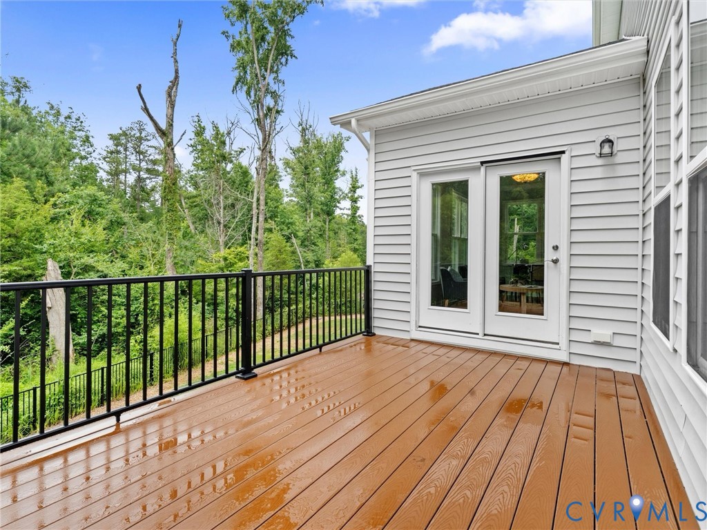 Exterior deck featuring wood-finish decking, black metal railings, and white siding
