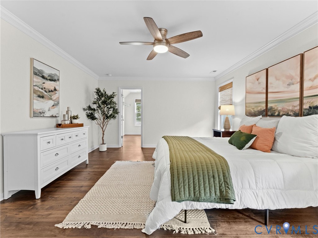 Spacious room featuring wood-finish flooring, white crown molding, and a ceiling fan with integrated lighting