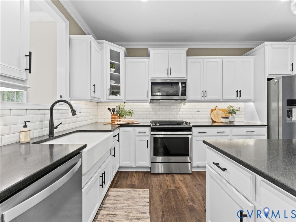 Modern kitchen featuring white cabinetry, dark countertops, and stainless steel appliances