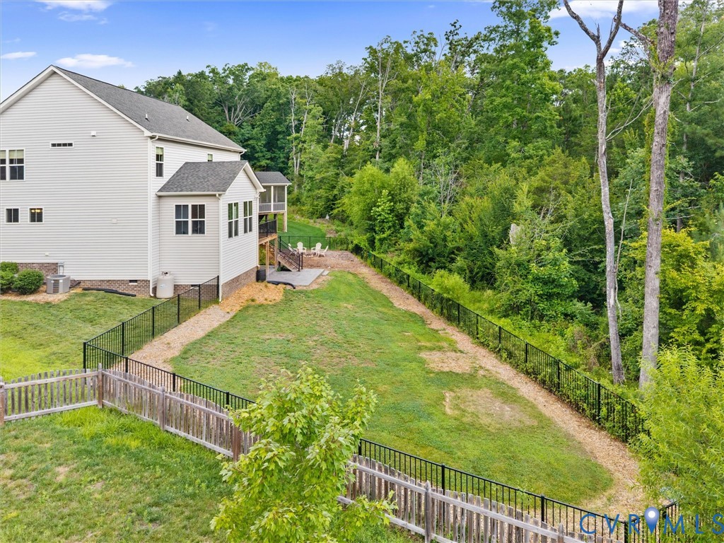 Expansive backyard featuring a manicured lawn, a gravel pathway, and mature trees