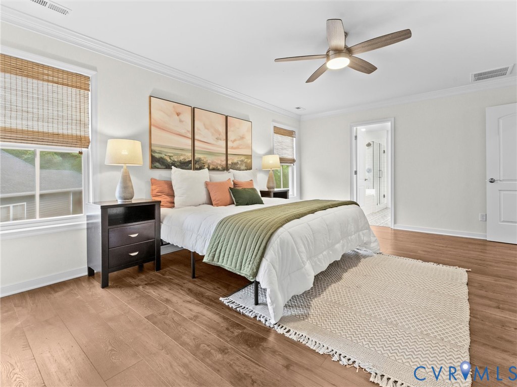 Spacious room featuring wood-finish flooring, white walls, and crown molding