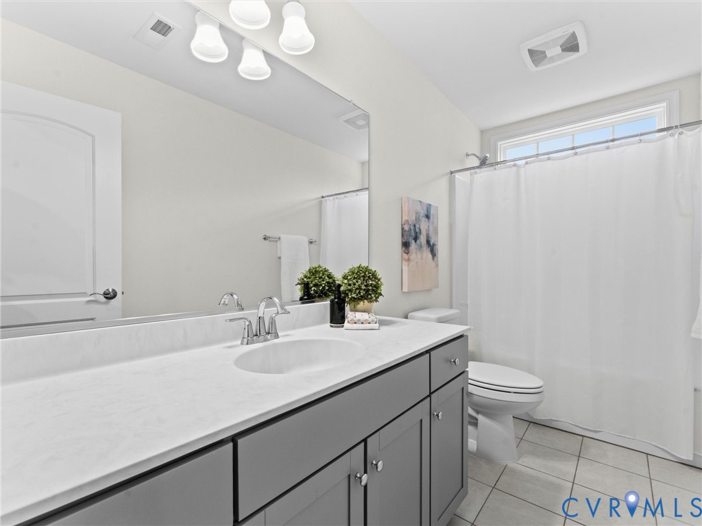 Bathroom featuring a vanity with a white countertop, undermount sink, and gray cabinetry