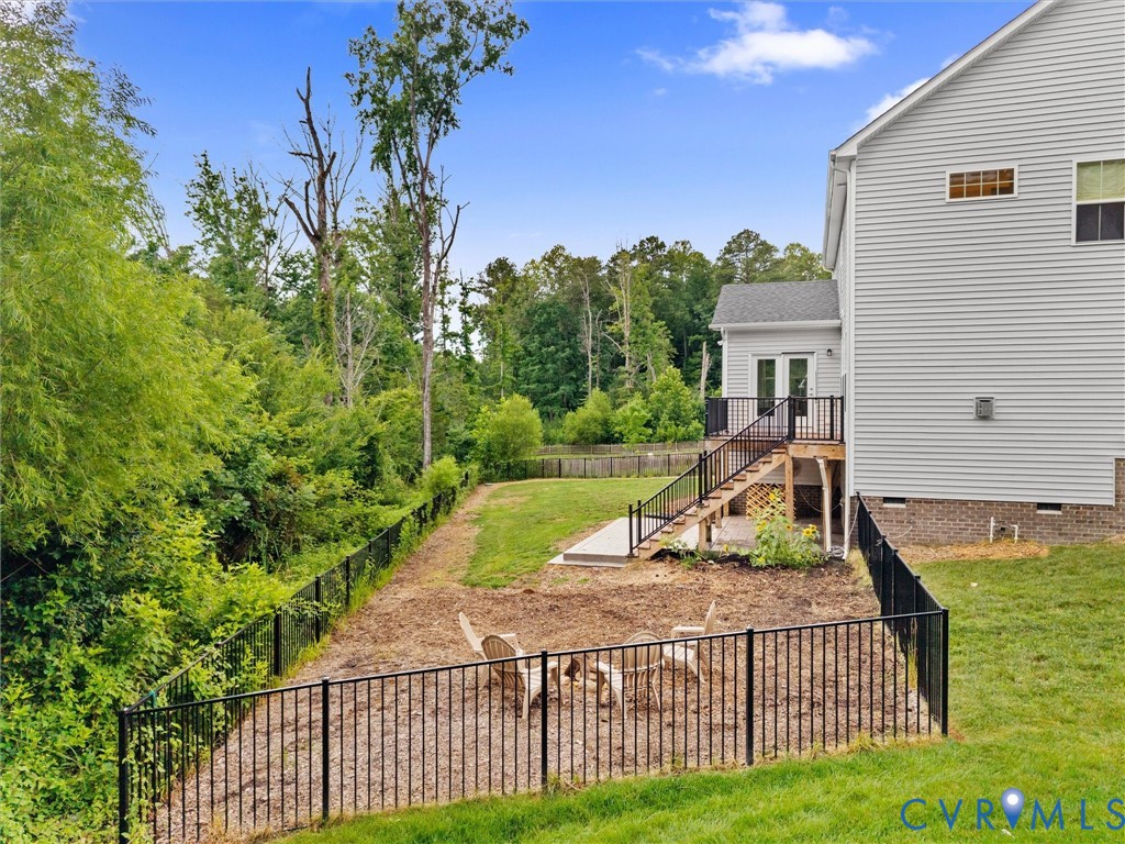 Expansive outdoor space featuring a multi-level fenced yard, a wooden deck with black railings, and a walk-out basement patio