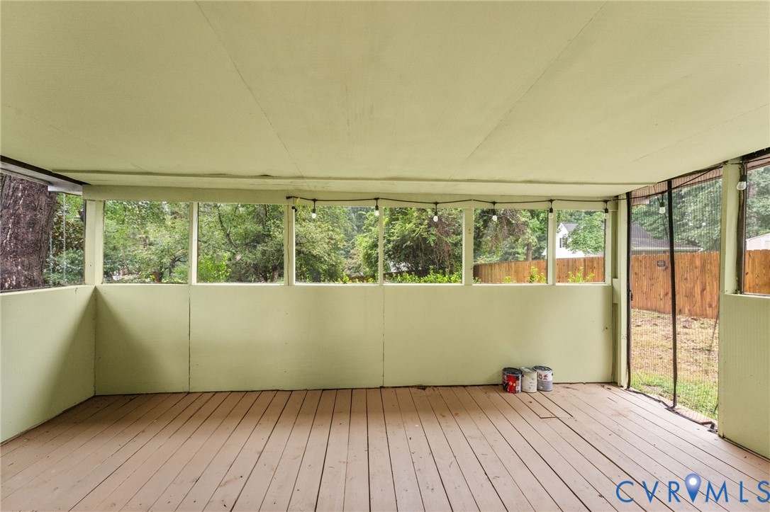 Screened-in porch featuring wood-finish flooring, half-wall enclosures, and integrated string lighting Screened-in porch featuring wood-finish flooring, half-wall enclosures, and integrated string lighting