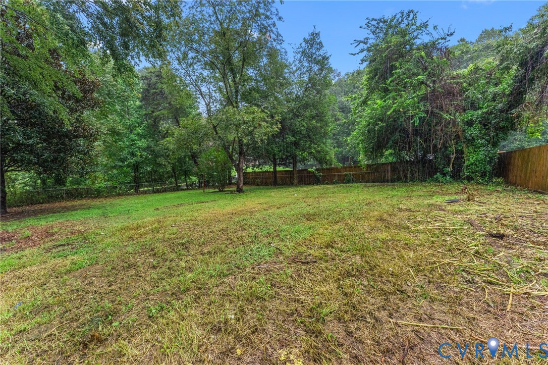 Expansive lot featuring a grass lawn, mature trees, and a wood privacy fence Expansive lot featuring a grass lawn, mature trees, and a wood privacy fence