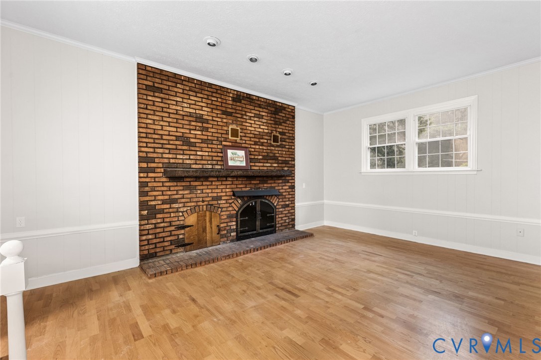 Living area featuring a floor-to-ceiling brick fireplace with a wood mantel, a brick hearth, and a black firebox