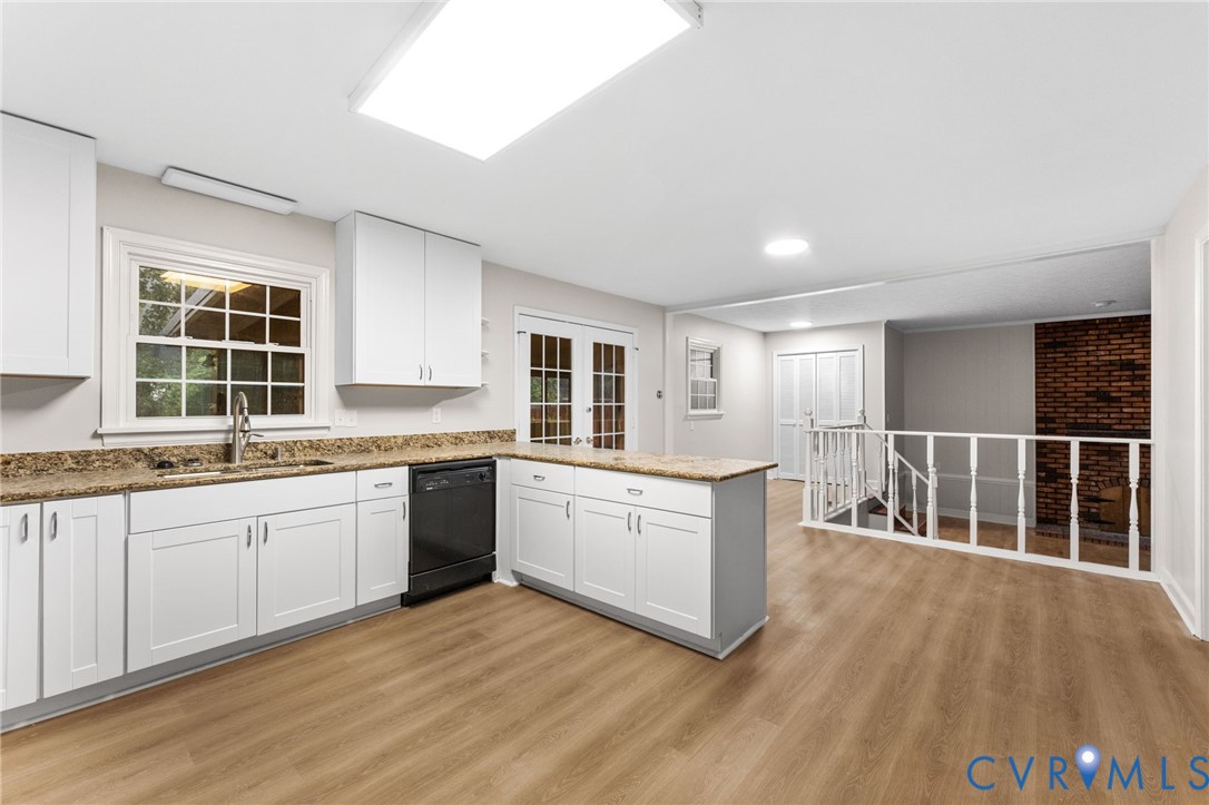 Kitchen featuring white cabinetry, a central island with countertop, stainless steel sink, and wood-finish flooring