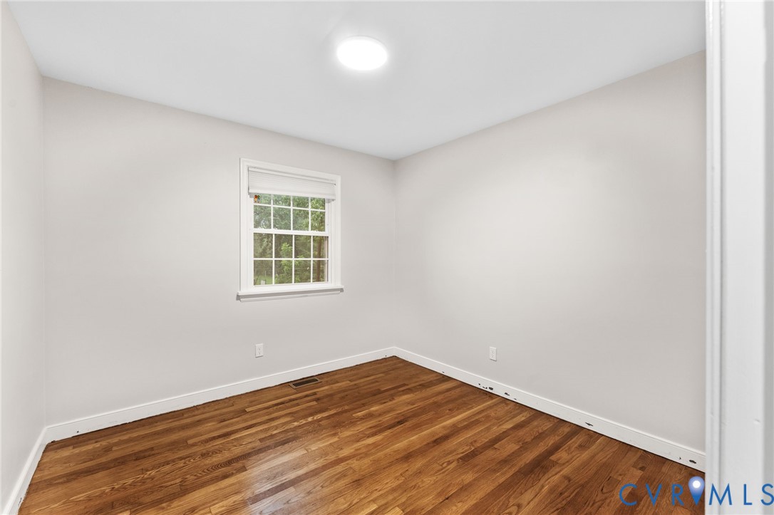 Room featuring wood-finish flooring, white baseboards, and neutral wall tones