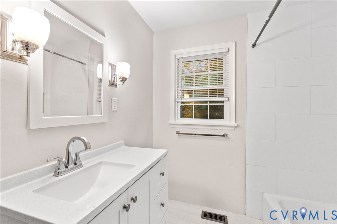Bathroom featuring a white vanity with integrated sink, chrome faucet, and a rectangular mirror