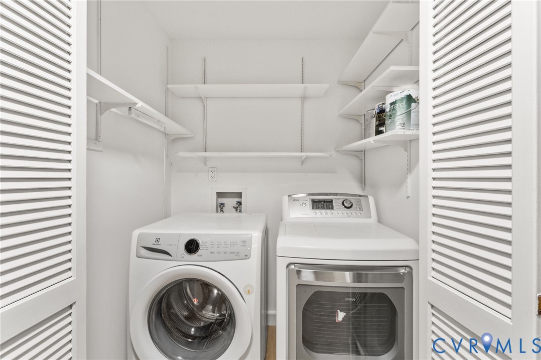 Dedicated laundry closet featuring a front-load washer, a dryer, and built-in adjustable shelving