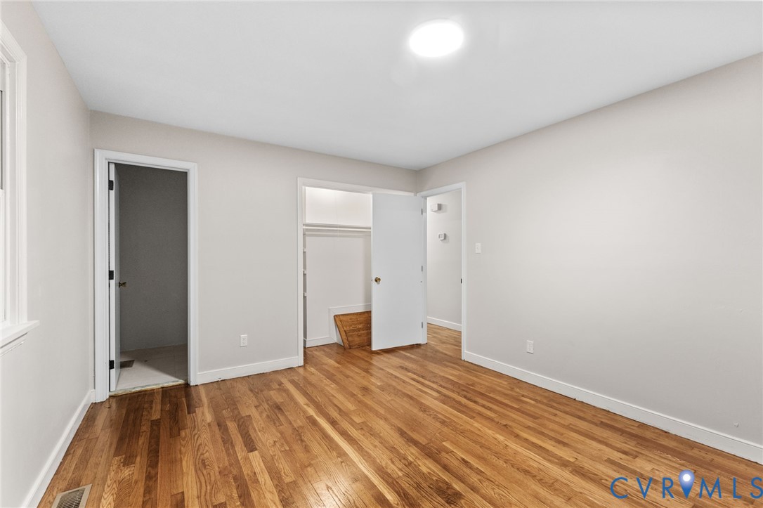 Spacious room featuring wood-finish flooring, light neutral wall paint, and white trim