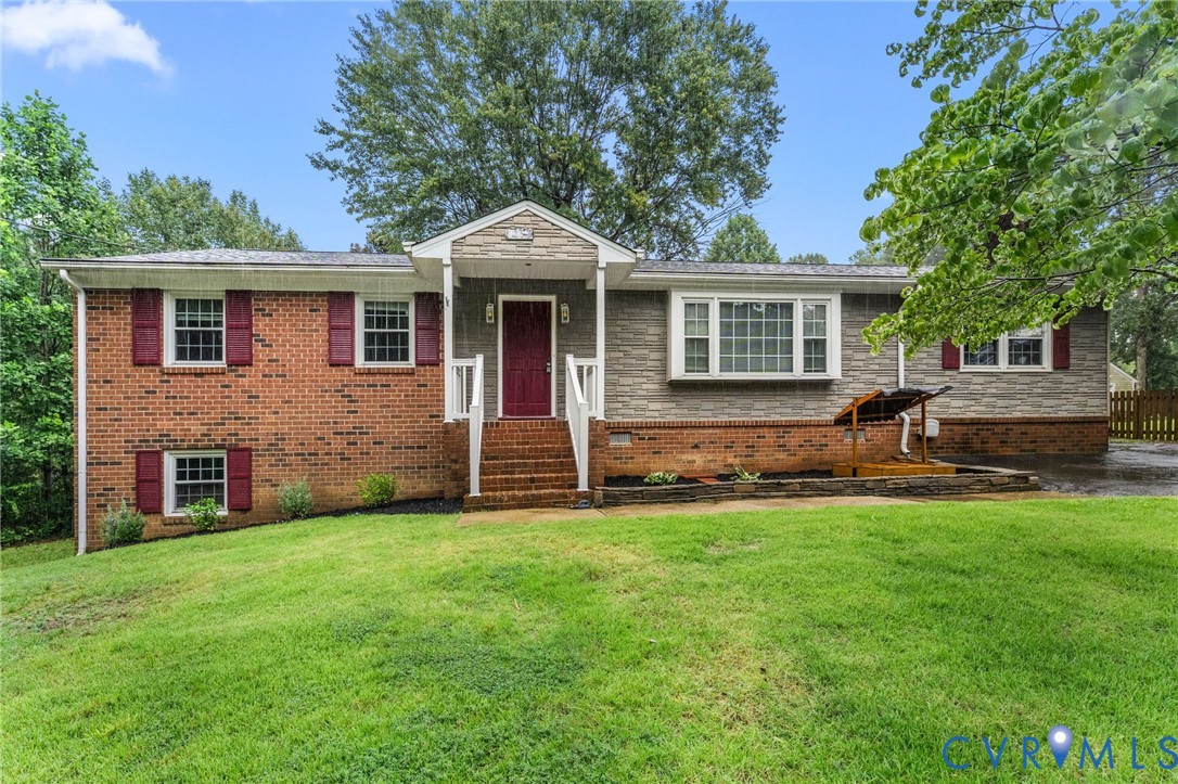 Split-level home featuring a brick and stone veneer facade, a covered front entry with white railings, and a red front door