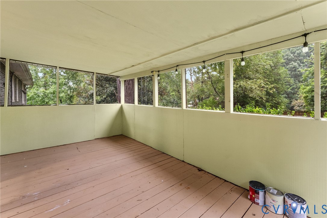 Expansive screened-in porch featuring wood-finish flooring and string lighting Expansive screened-in porch featuring wood-finish flooring and string lighting