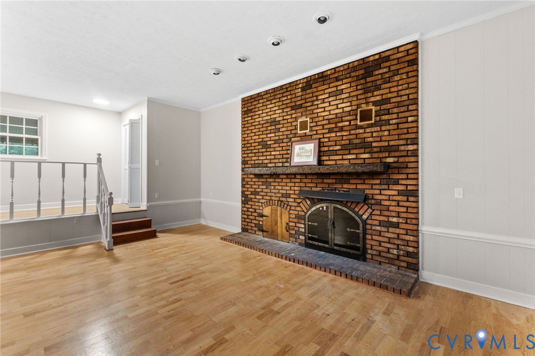 Spacious living area featuring a prominent brick fireplace with a dark wood mantel and metal-framed hearth