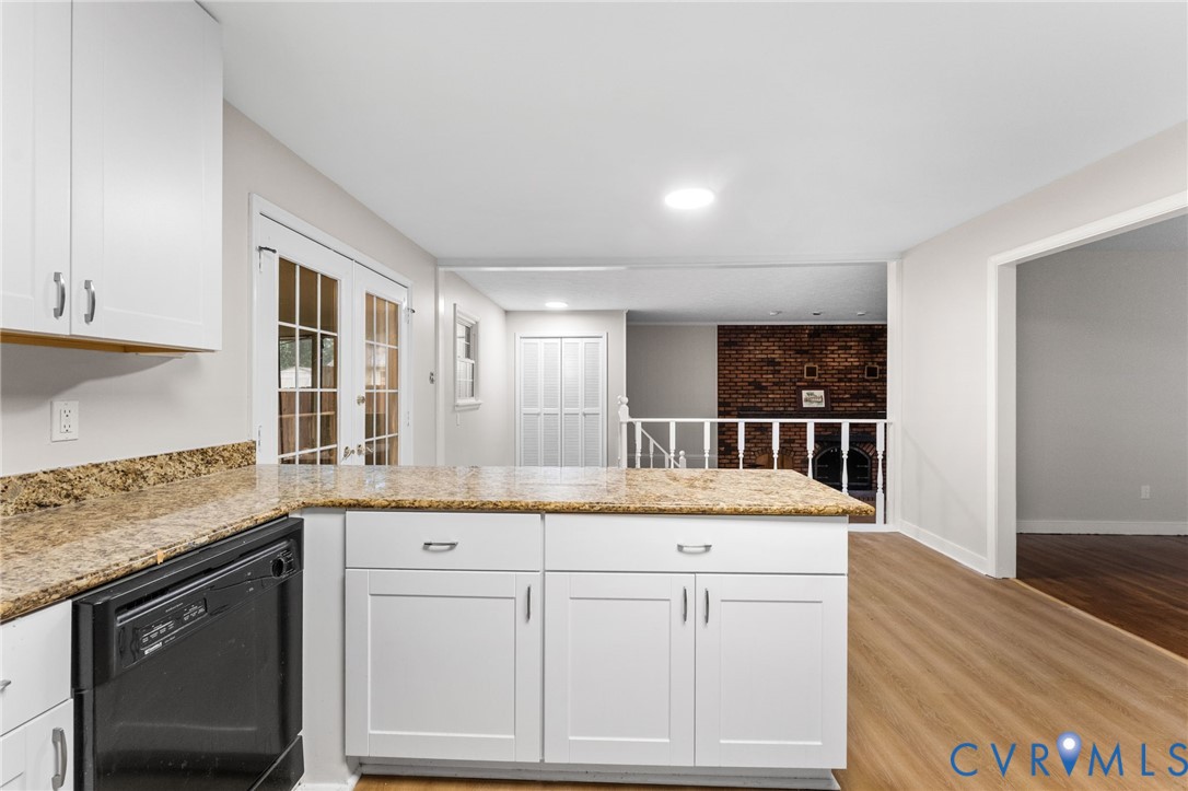 Kitchen with white shaker cabinetry, speckled countertops, and an integrated dishwasher