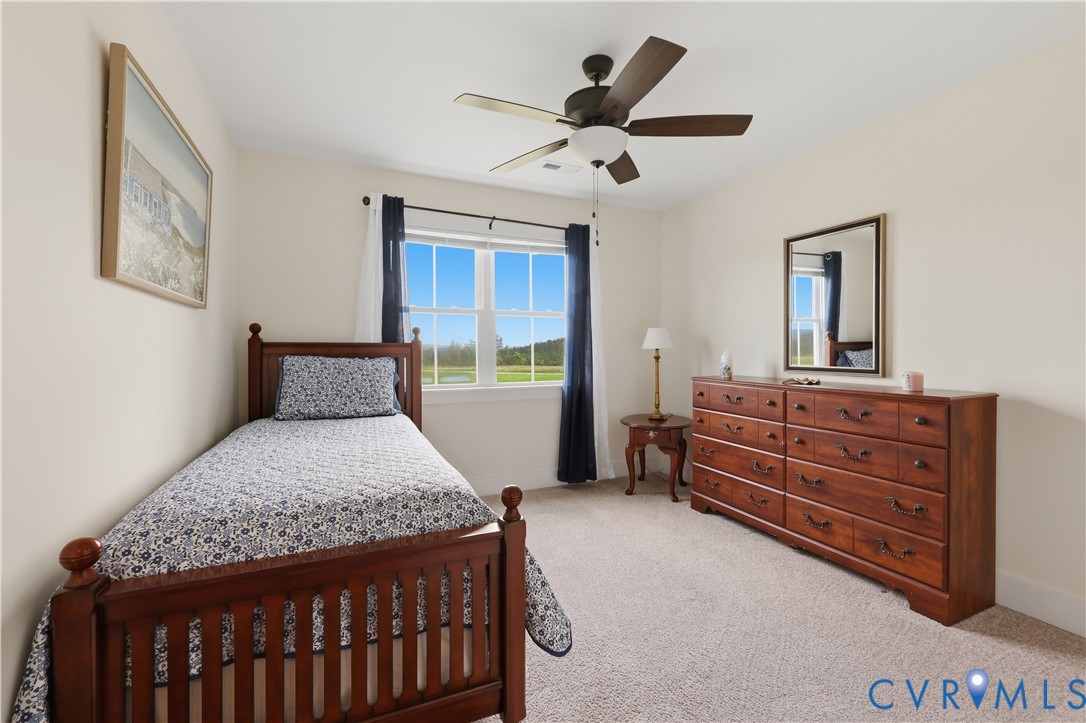 Carpeted room with a ceiling fan, a double-hung window with dark curtains, and light-toned walls