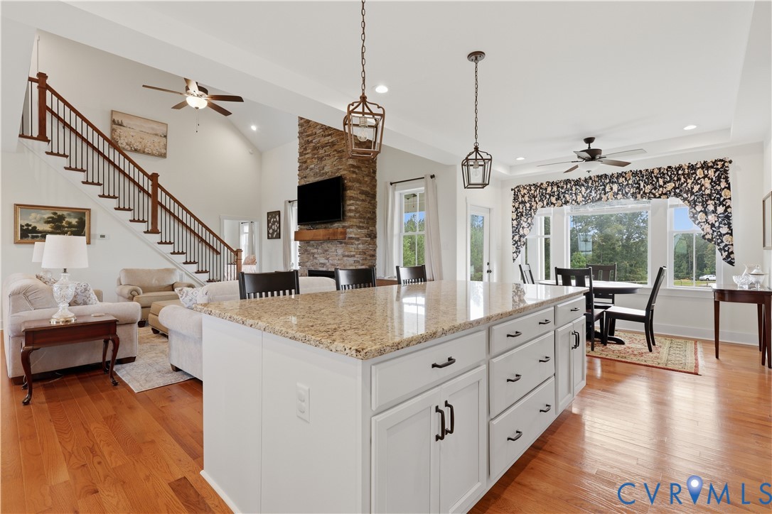 Open-concept living space featuring a large kitchen island with light-toned granite countertop and white cabinetry
