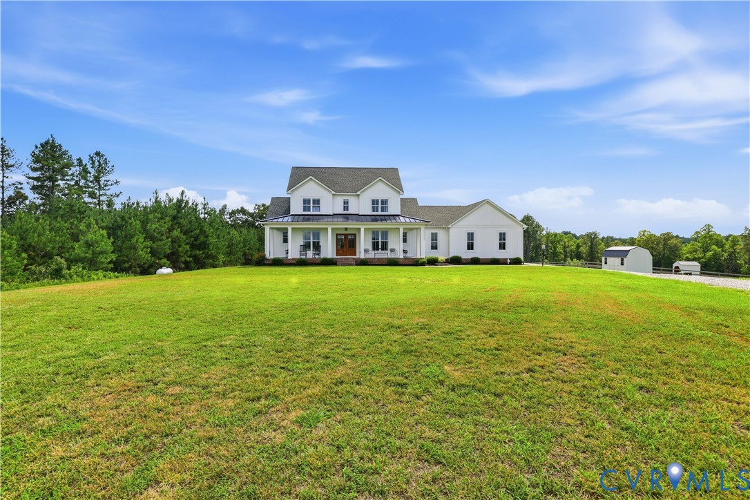 White two-story residence featuring a covered front porch with columns, dark roof, and a prominent front door
