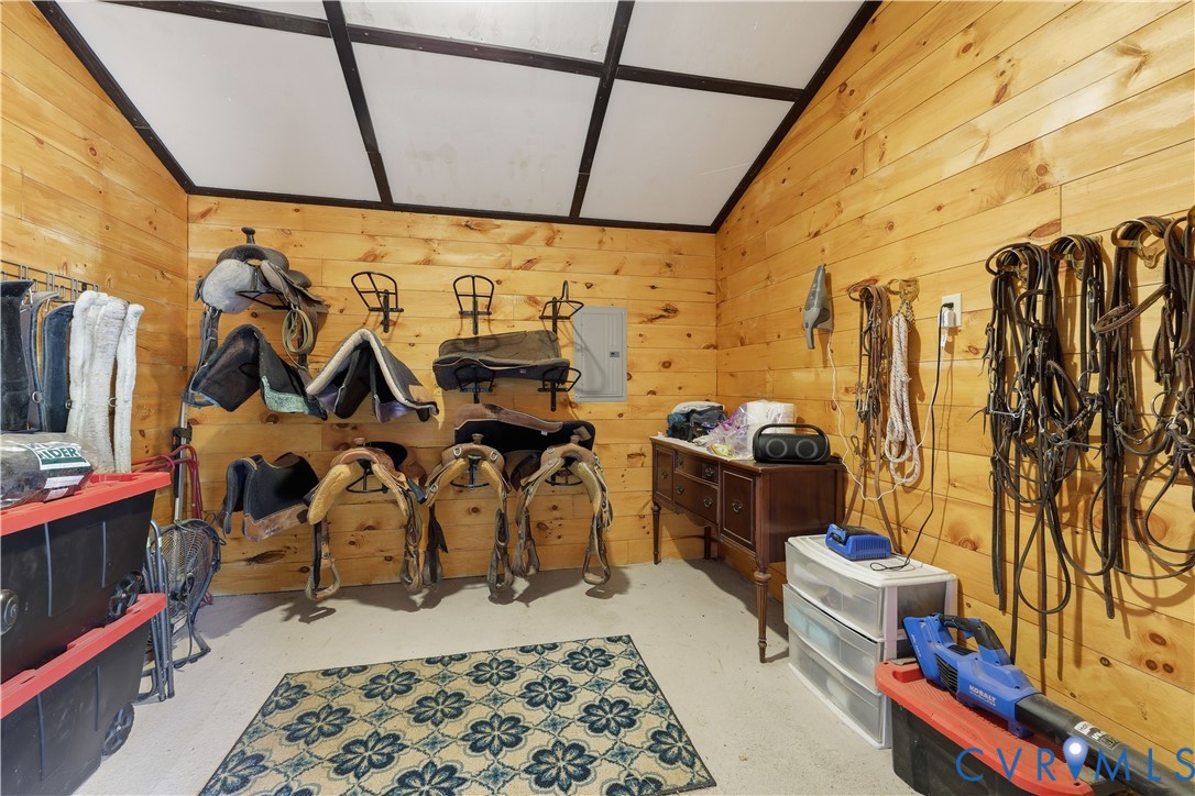 Wood-paneled room featuring a concrete floor, sloped ceiling with exposed beams, and ample wall storage