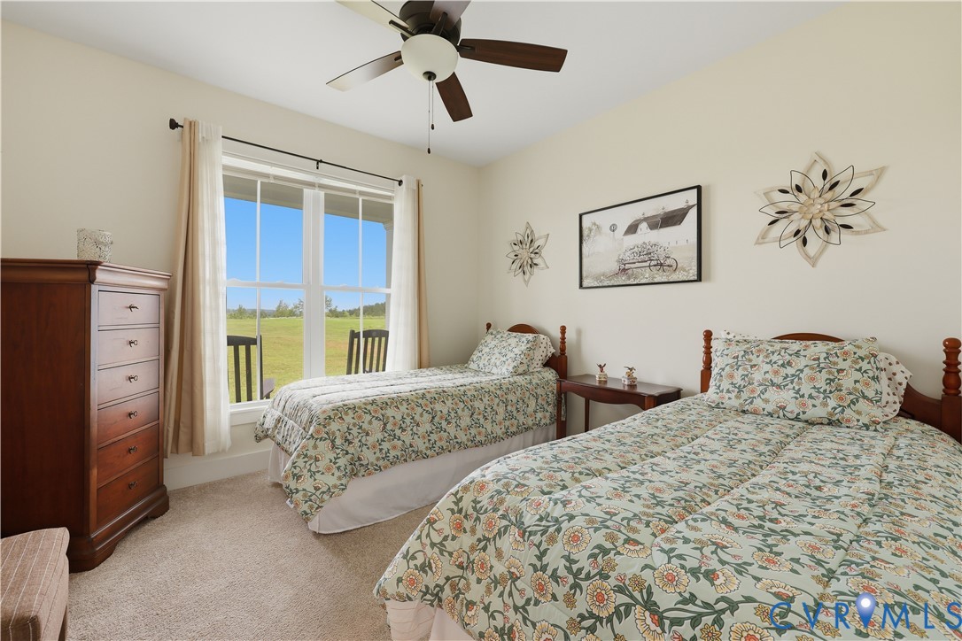 Carpeted room with a large window offering expansive outdoor scenery, neutral wall tones, and a ceiling fan with integrated lighting