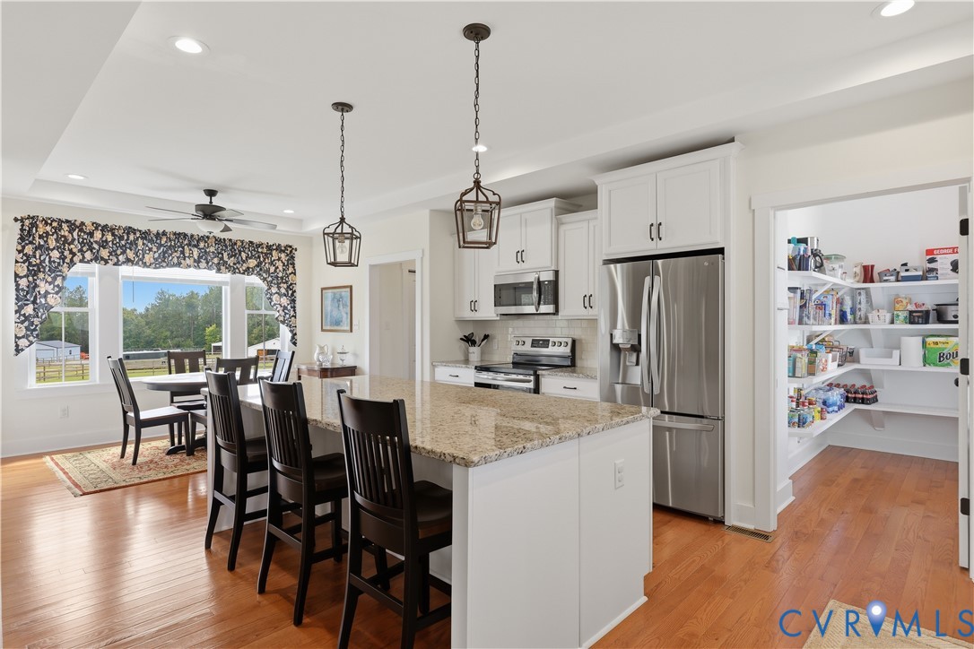 Kitchen featuring a large island with a stone countertop, white cabinetry, and stainless steel appliances