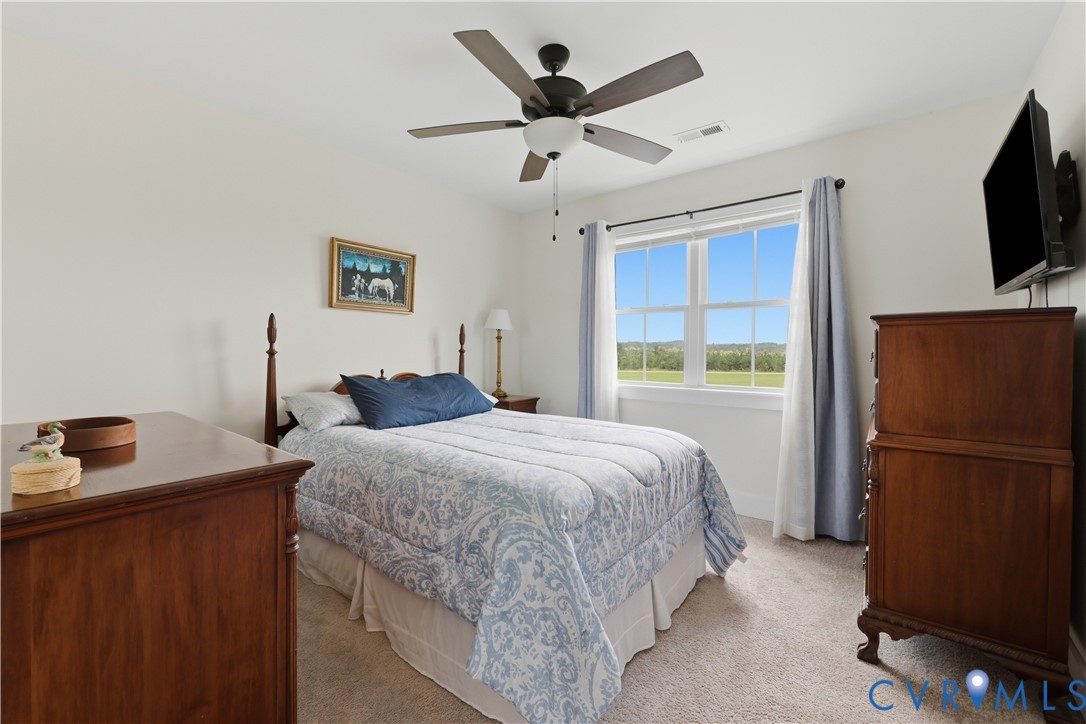 Carpeted interior room featuring a multi-pane window, ceiling fan with integrated lighting, and light-colored walls