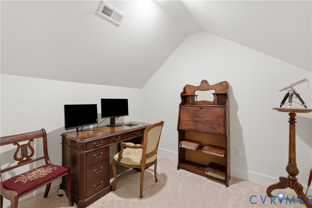 Carpeted room with sloped ceilings and white walls, featuring a white baseboard trim