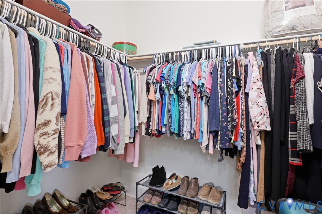 Walk-in closet featuring floor-to-ceiling hanging rods, corner shelving, and light-toned walls