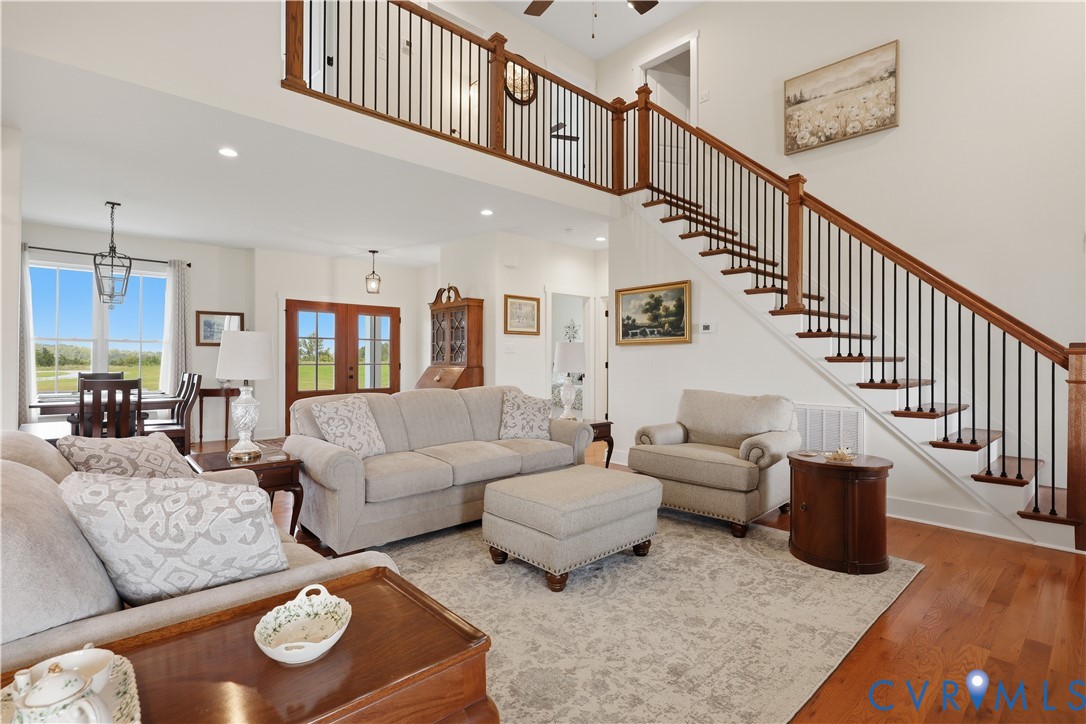 Spacious living area featuring wood-finish flooring, a grand staircase with dark iron balusters and wood handrails, and an open-concept design