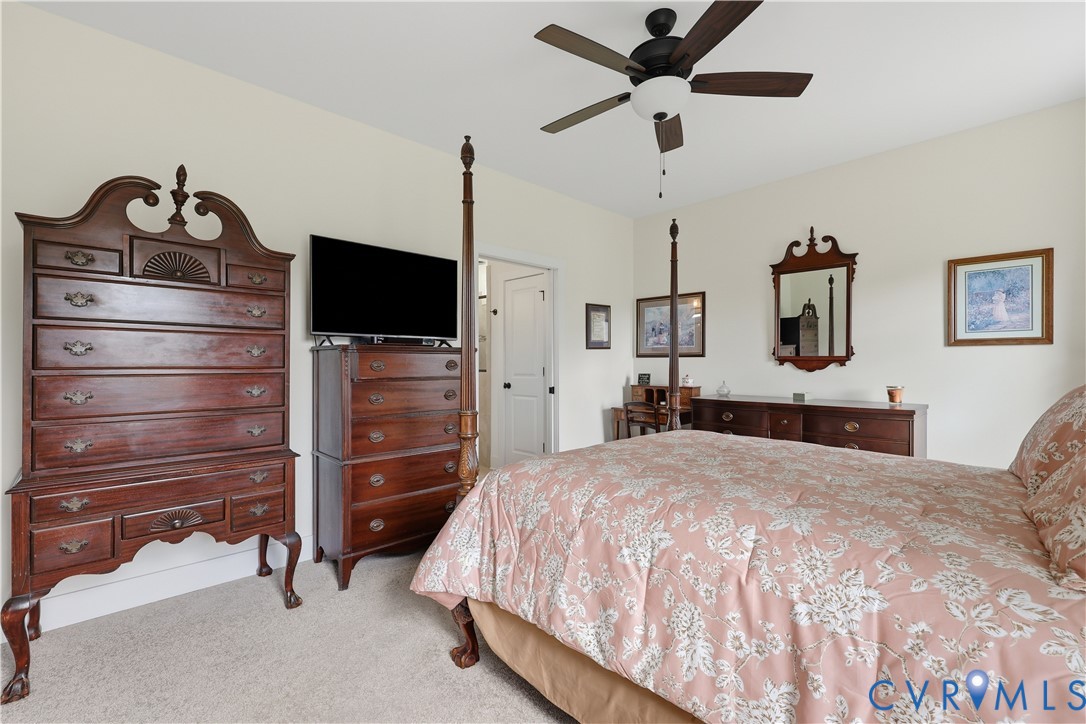 Carpeted bedroom featuring neutral wall paint, a ceiling fan with integrated lighting, and white trim