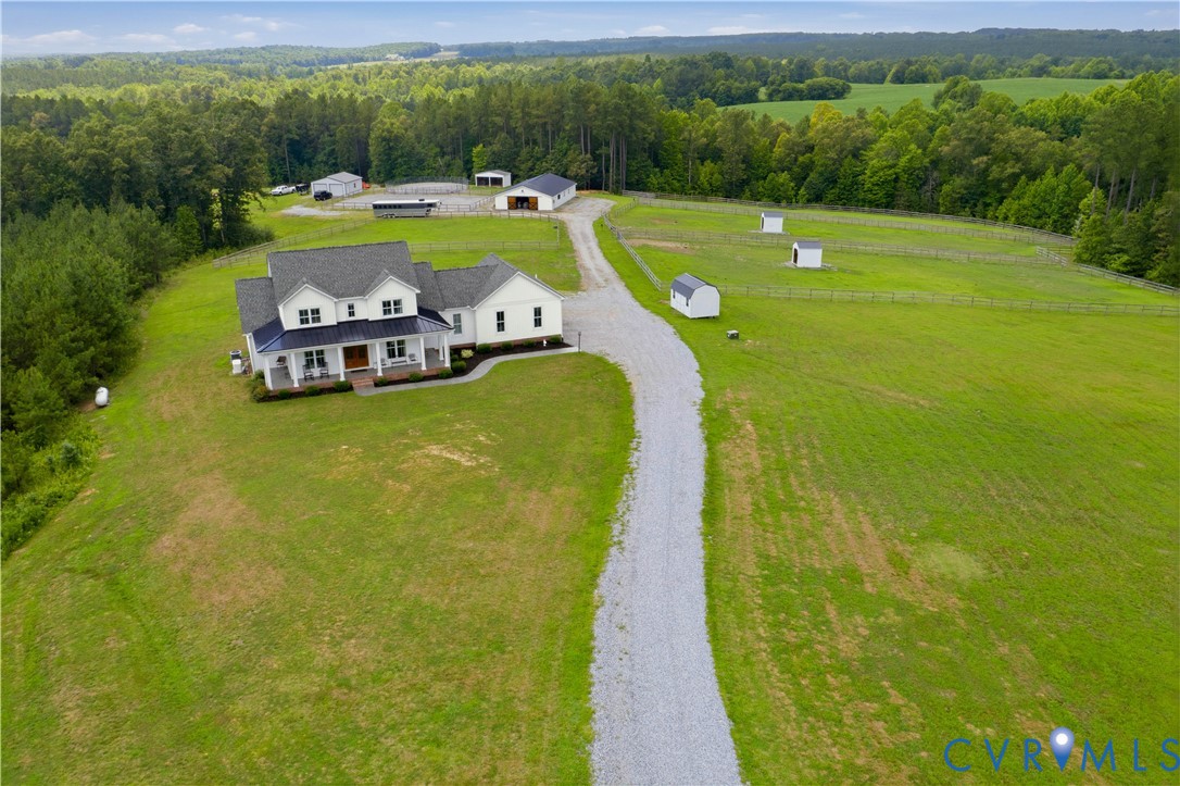 Expansive property featuring a white residence with a dark roof and a full-width front porch