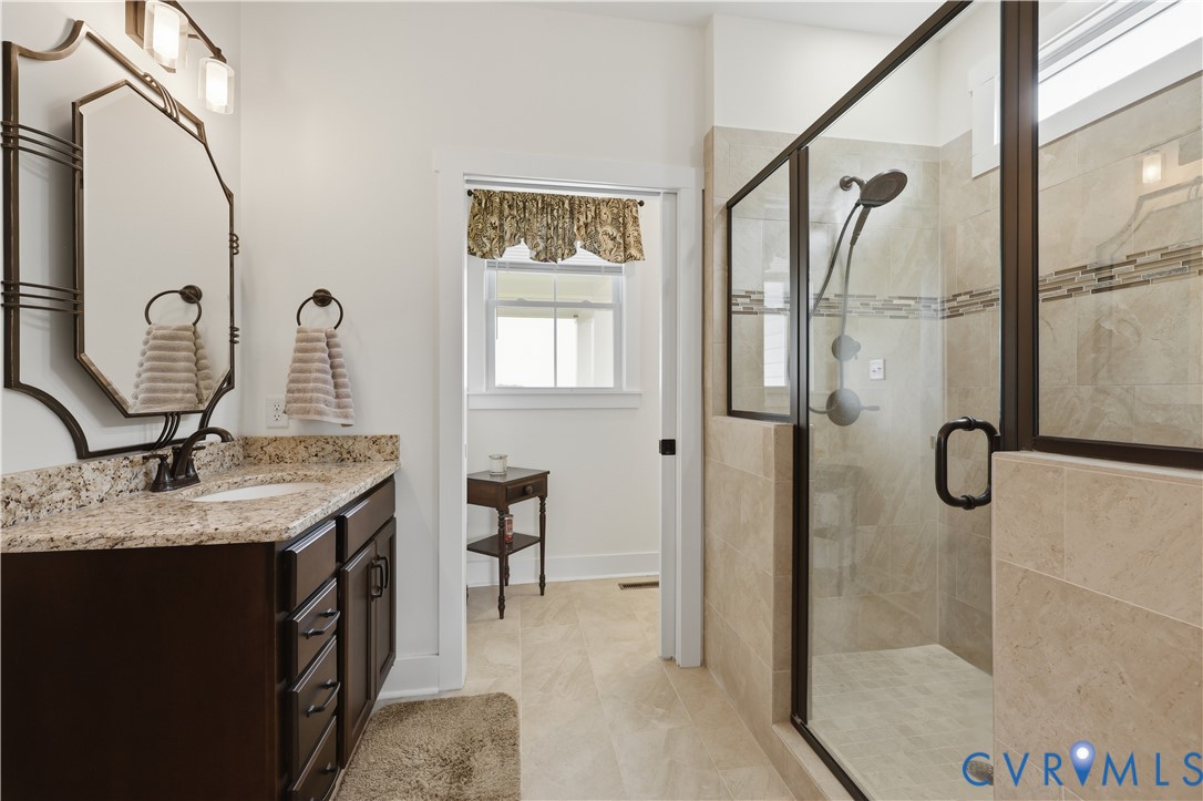Bathroom featuring a dark wood vanity with a granite countertop, a rectangular undermount sink, and an ornate framed mirror