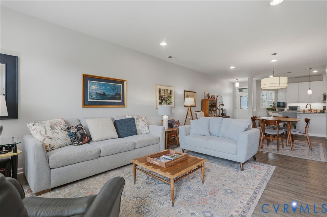 Open-concept living area with wood-finish flooring, recessed lighting, and a neutral color palette