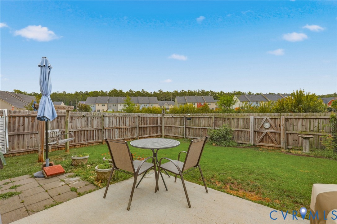 Private backyard featuring a concrete patio, wood privacy fencing, and a grassy area