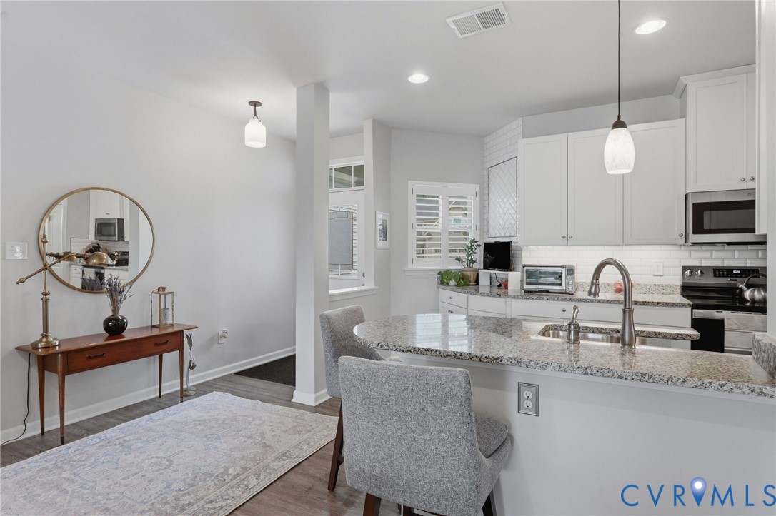 Modern kitchen featuring white cabinetry, stainless steel appliances, a white subway tile backsplash, and granite countertops