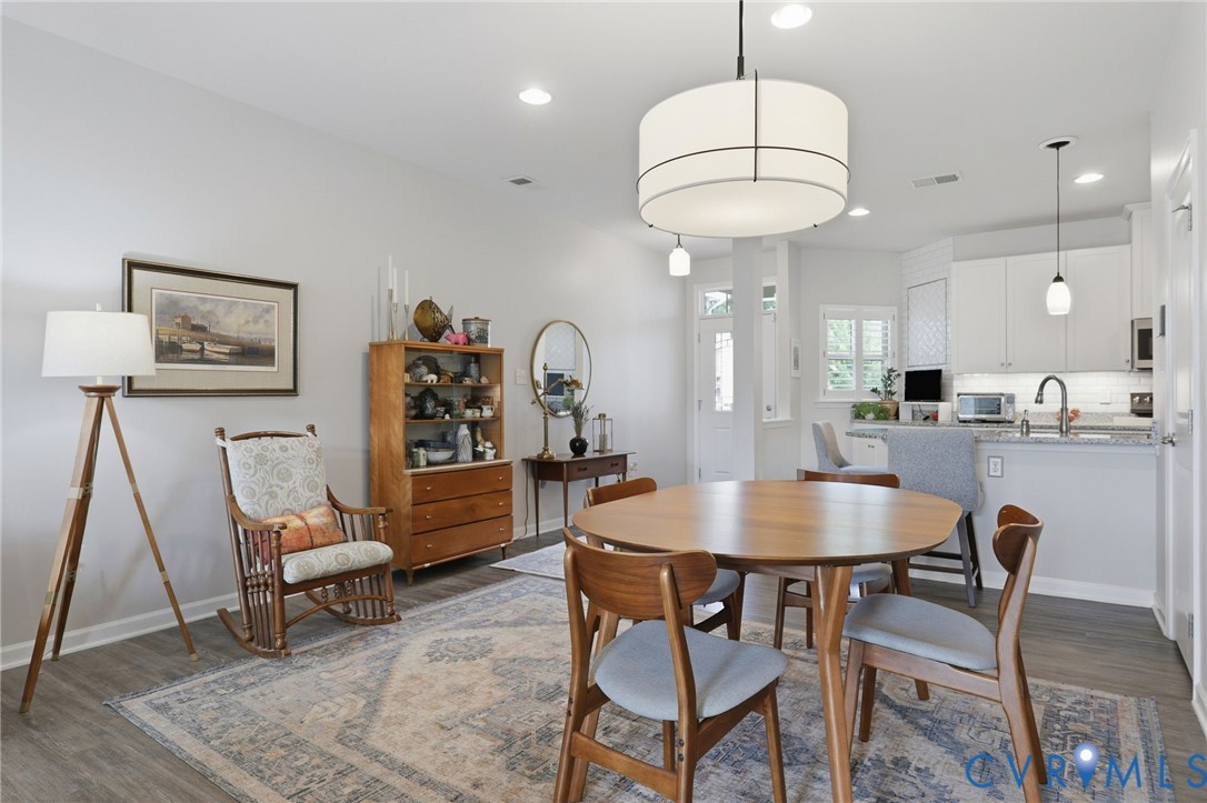 Open-concept dining and kitchen area featuring a drum pendant light fixture, recessed lighting, and wood-finish flooring