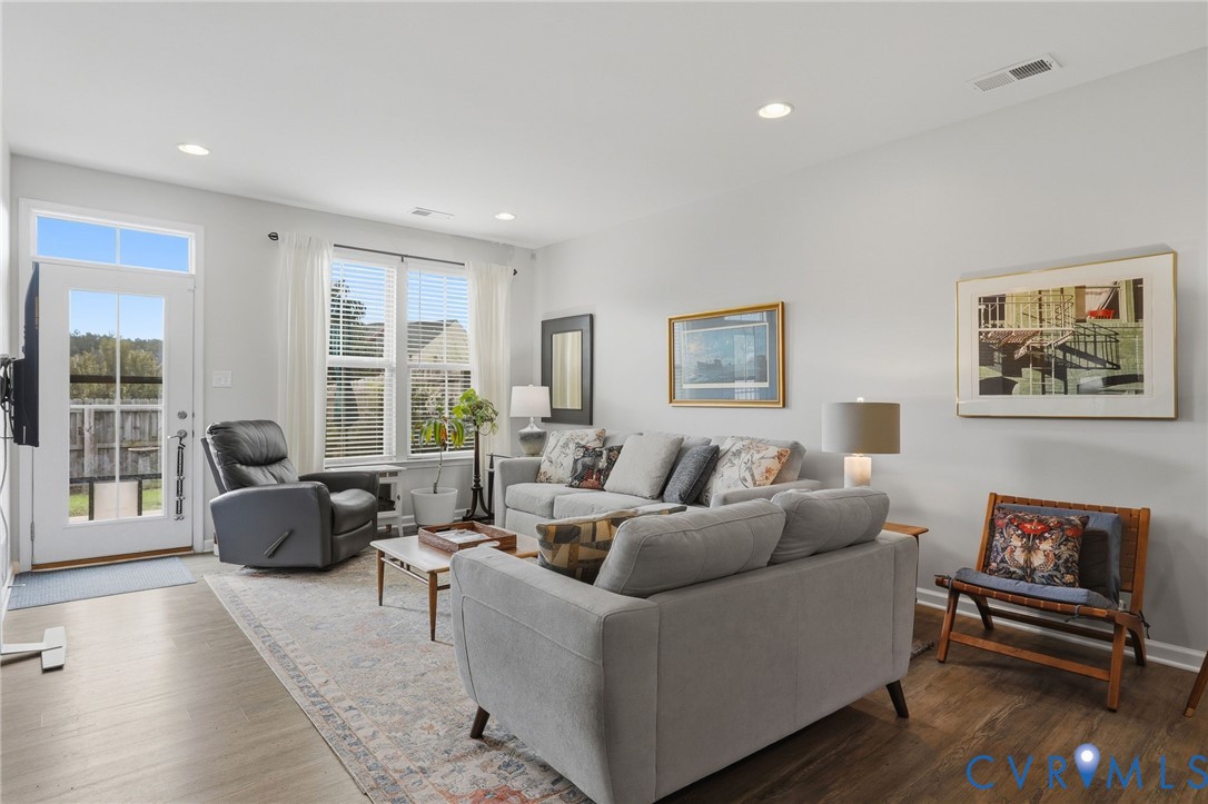 Spacious living area featuring wood-finish flooring, recessed lighting, and ample natural light from multiple windows