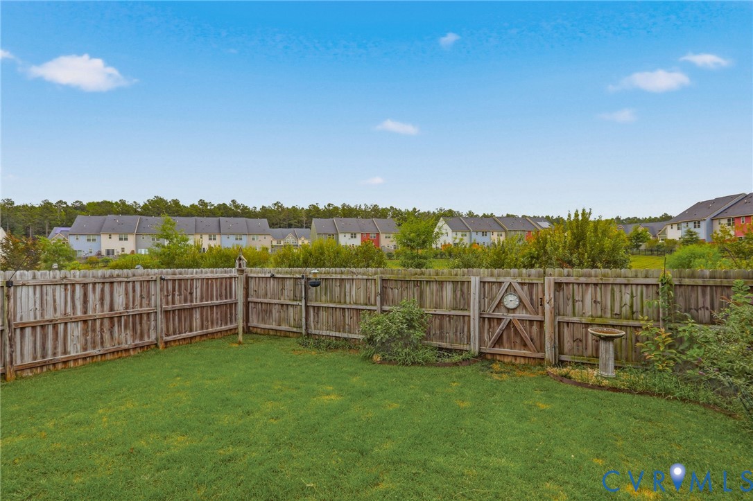 Fenced backyard featuring a manicured lawn, wood privacy fencing, and mature perimeter landscaping