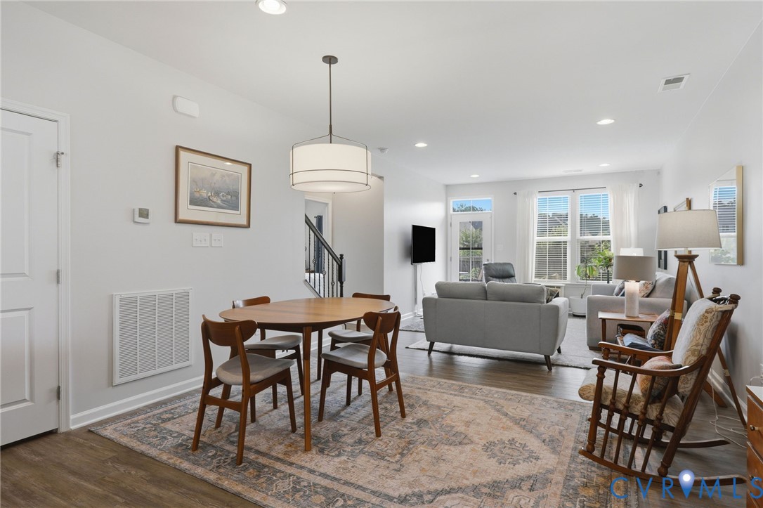 Open-concept living space featuring wood-finish flooring, recessed lighting, and a drum pendant light fixture